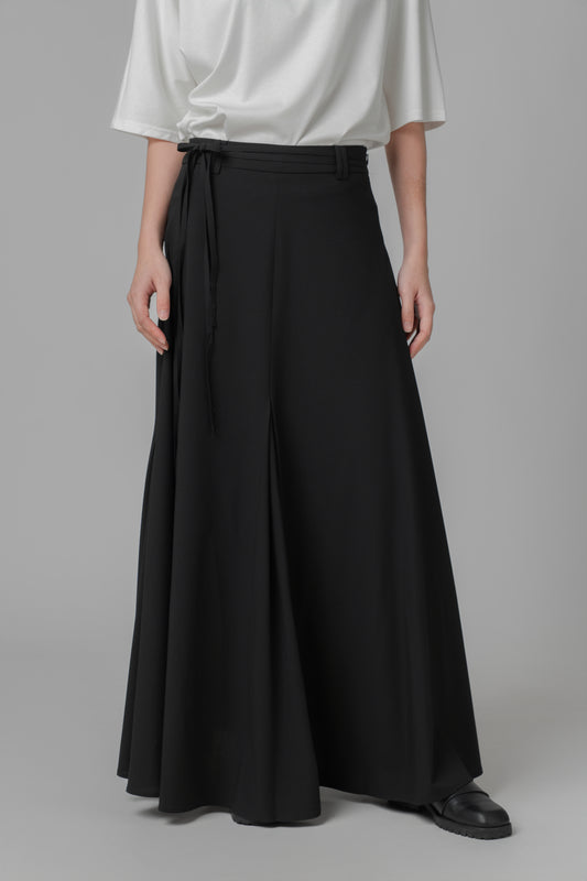 Person wearing black A-line skirt on a gray background