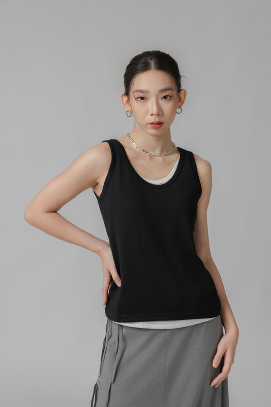 Woman wearing a black two-layer sleeveless top and gray skirt