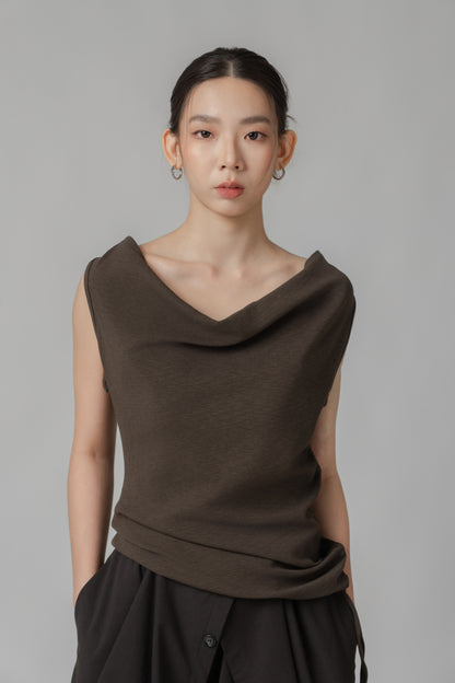 Woman wearing a dark brown sleeveless top with a draped design 