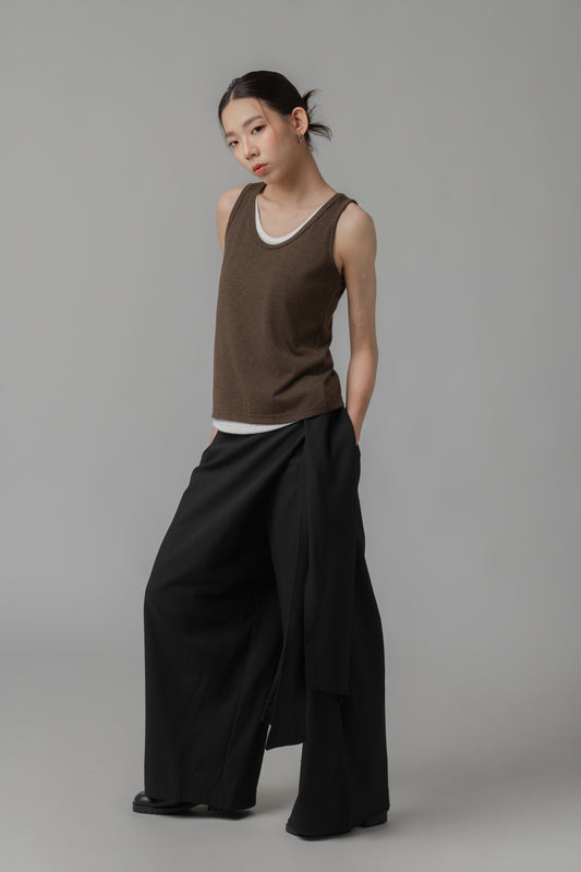 Woman wearing a brown top and black wide-leg pants with a draped front panel and a side waist tie