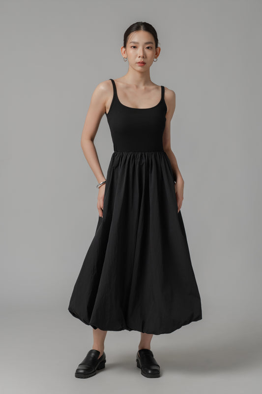 Woman wearing a midi black dress with ribbed bodice and voluminous bubble hem skirt