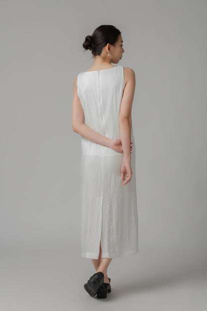 Woman showing the back of a white sleeveless crinkled column dress 